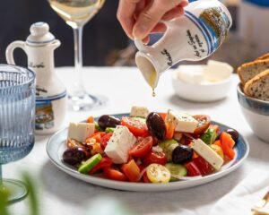 Alimentación consciente: ensalada mediterránea con feta, tomates y aceite de oliva vertido con presencia