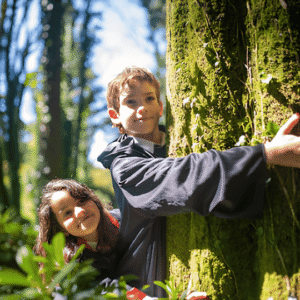 Niños abrazando un árbol durante una experiencia de baño de bosque en familia con Awakenova.