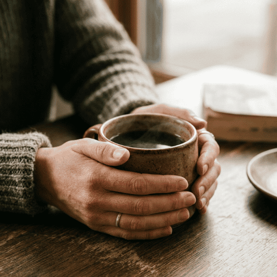Cómo conocerse a uno mismo: manos sosteniendo una taza en un momento de pausa y reflexión | Proyecto Awakenova
